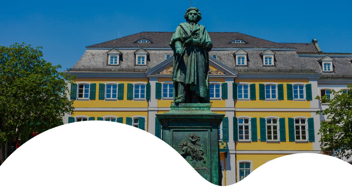 systemische-coaching-ausbildung-inkonstellation-bonn-hero Denkmal in Bonner Innenstadt vor gelbem Gebäude